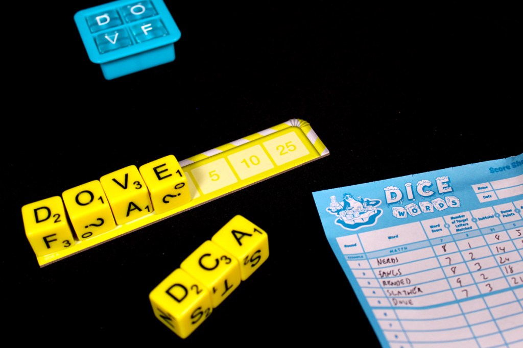 A close-up of a scoring sheet from the game Dice Words, featuring yellow letter dice showing the letters 'D', 'O', 'V', 'E', 'F', 'A', along with a scoring track indicating 5, 10, and 25 points.