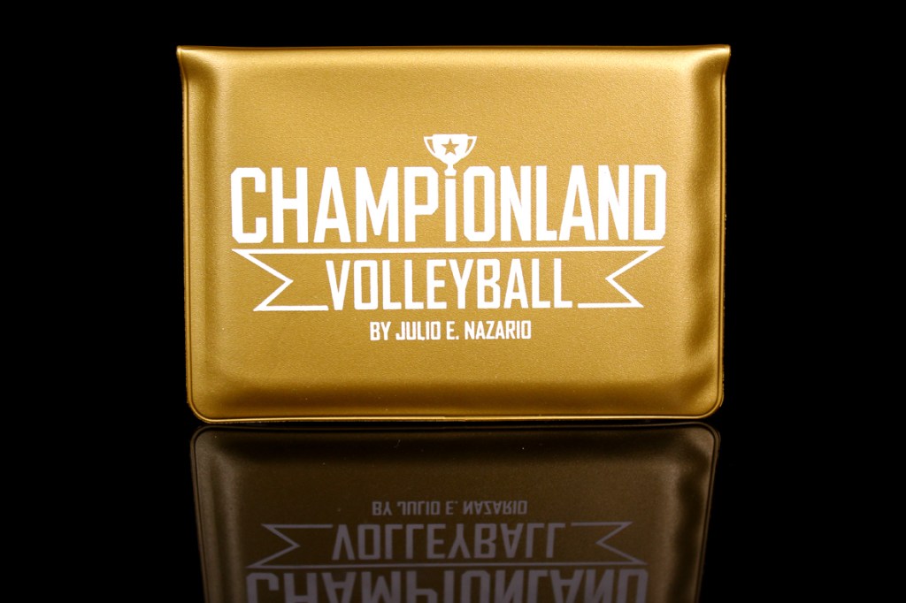 A gold-colored box featuring the title 'Championland: Volleyball' in bold white letters, with the subtitle 'by Julio E. Nazario' and a trophy icon, reflecting on a dark surface.