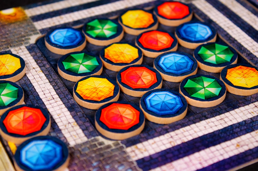 Colorful token pieces with geometric designs arranged on a board game grid.