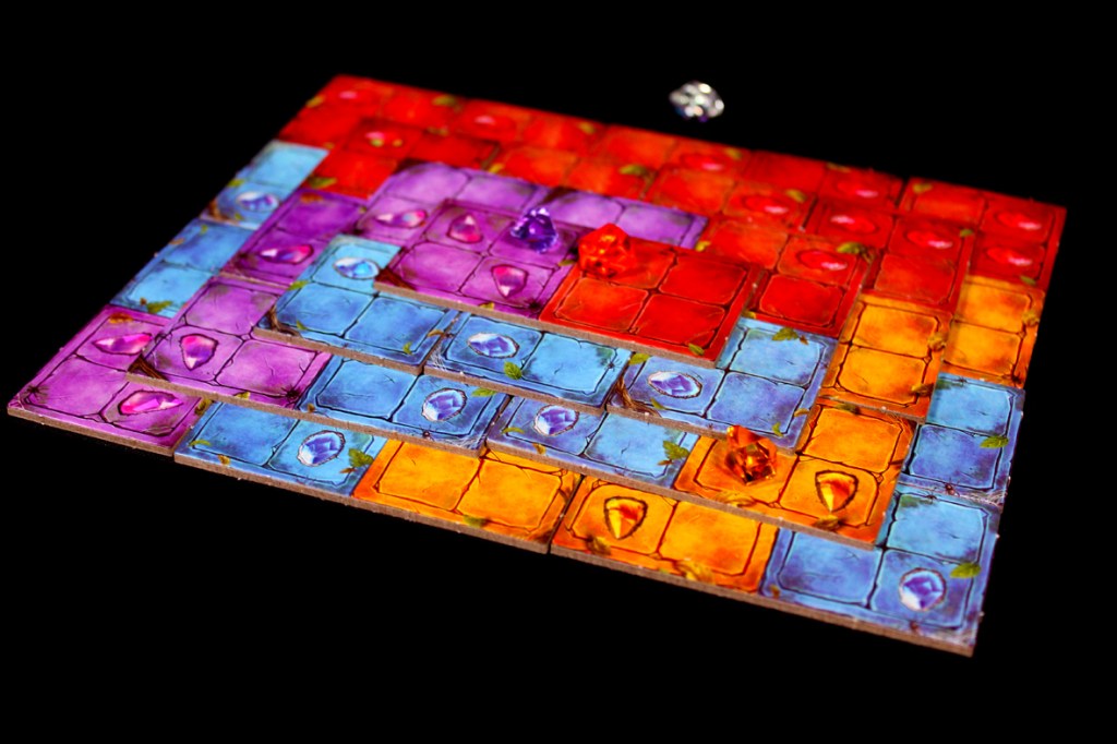 A colorful board game layout showcasing interconnected tiles in various shades of blue, purple, red, and orange, with gem pieces placed on the tiles.