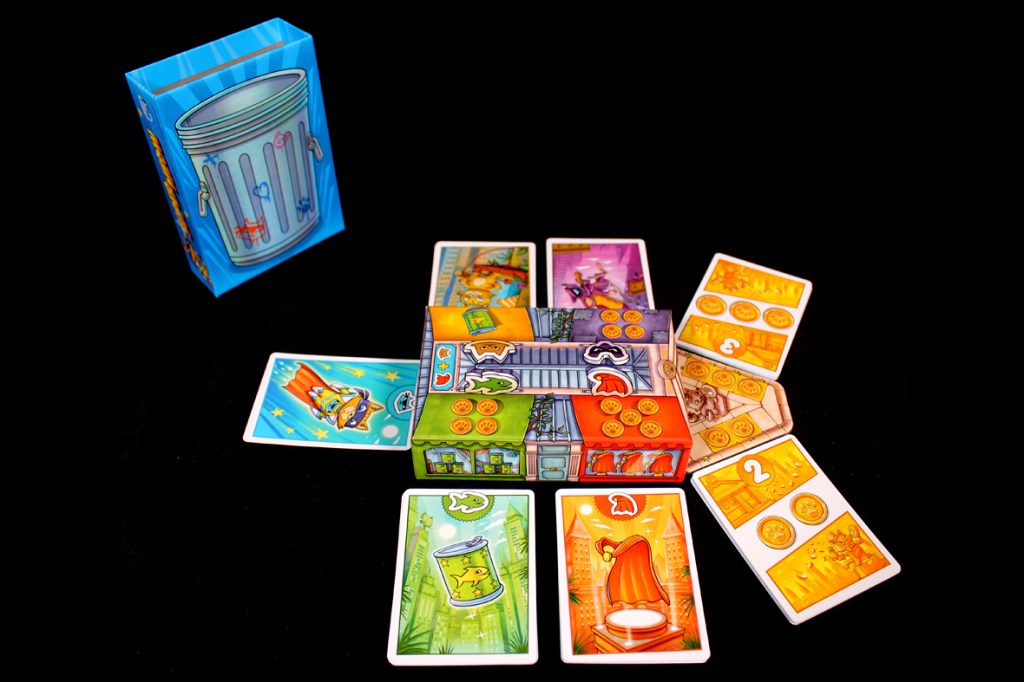 Colorful board game setup featuring a trash can box and various game cards laid out, showcasing gameplay elements for 'Super Meow'.