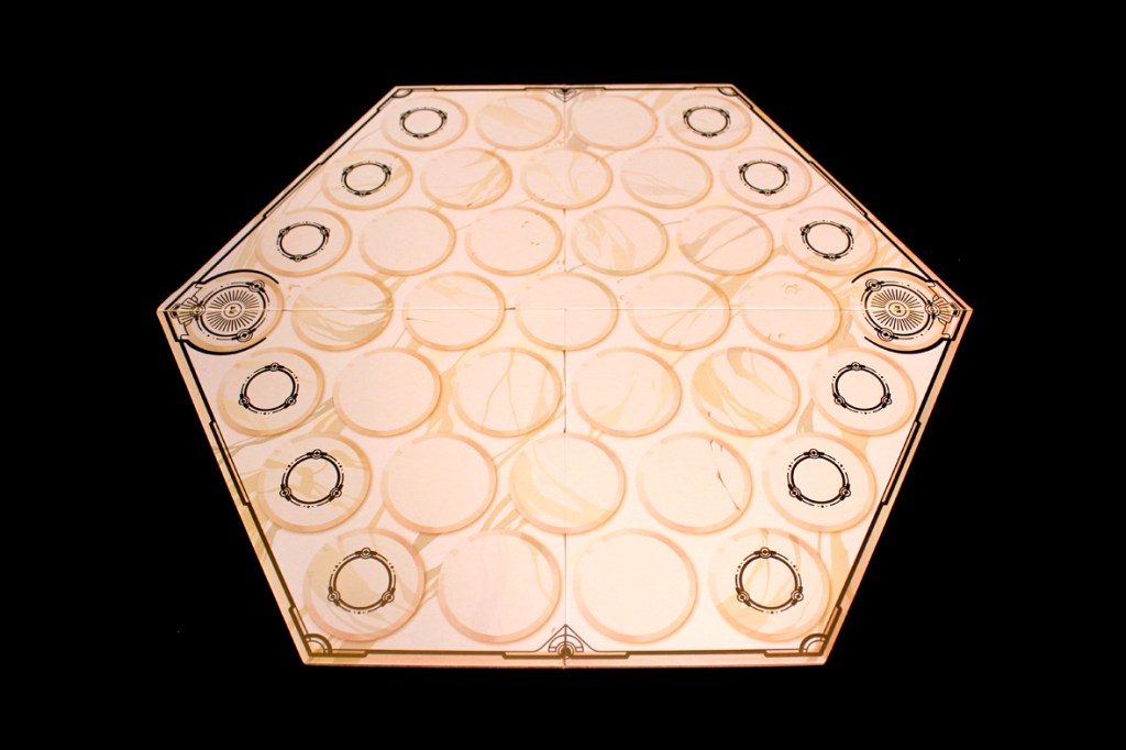 A hexagonal game board featuring circular spaces and decorative borders, set against a black background.
