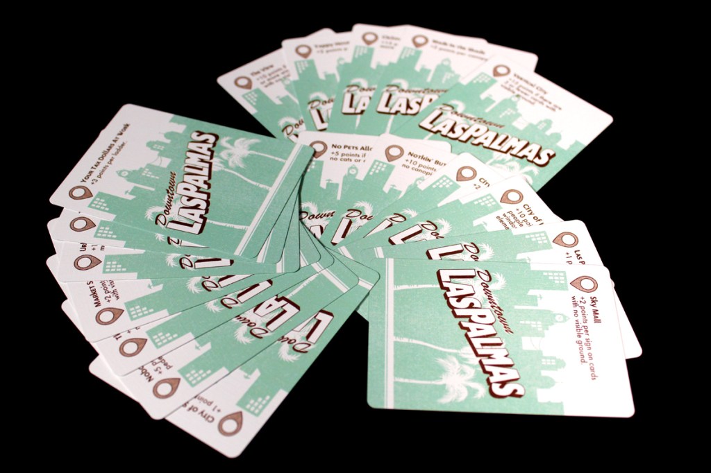 A fan of playing cards spread out, featuring a design with 'Laspalmas' and city skyline graphics in green and white.