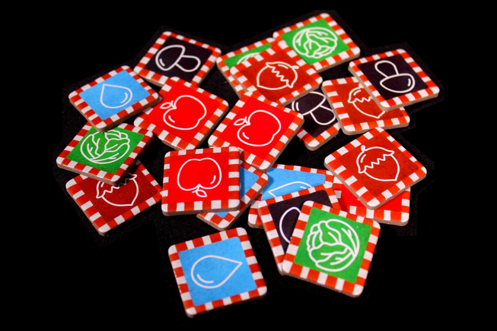 Colorful game tiles featuring various fruits and vegetables, scattered on a black background.