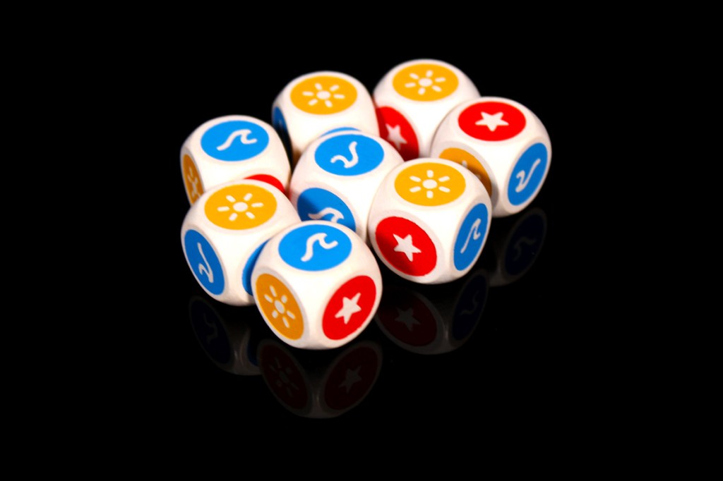 A close-up of colorful dice featuring various symbols, including stars and flowers, arranged on a reflective black surface.