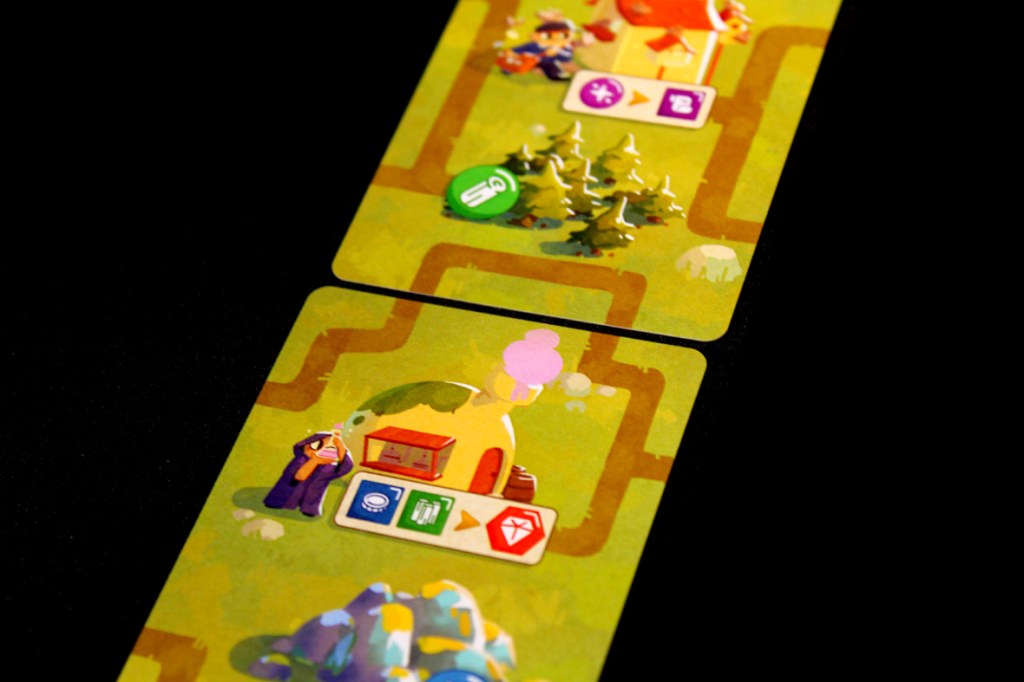 Two game cards from A Dragon's Gift featuring colorful art and icons representing gameplay mechanics, set against a dark background.