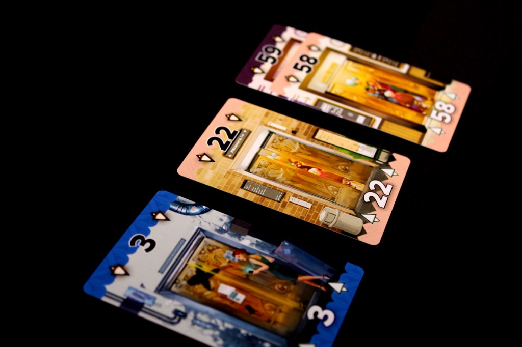 Three playing cards displayed on a black background, featuring colorful illustrations and numbers 3, 22, and 58.