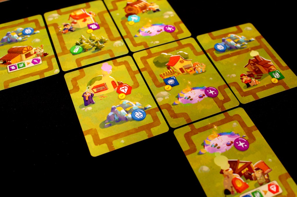 Game setup layout for 'A Dragon's Gift' featuring various village cards and resources on a tabletop.