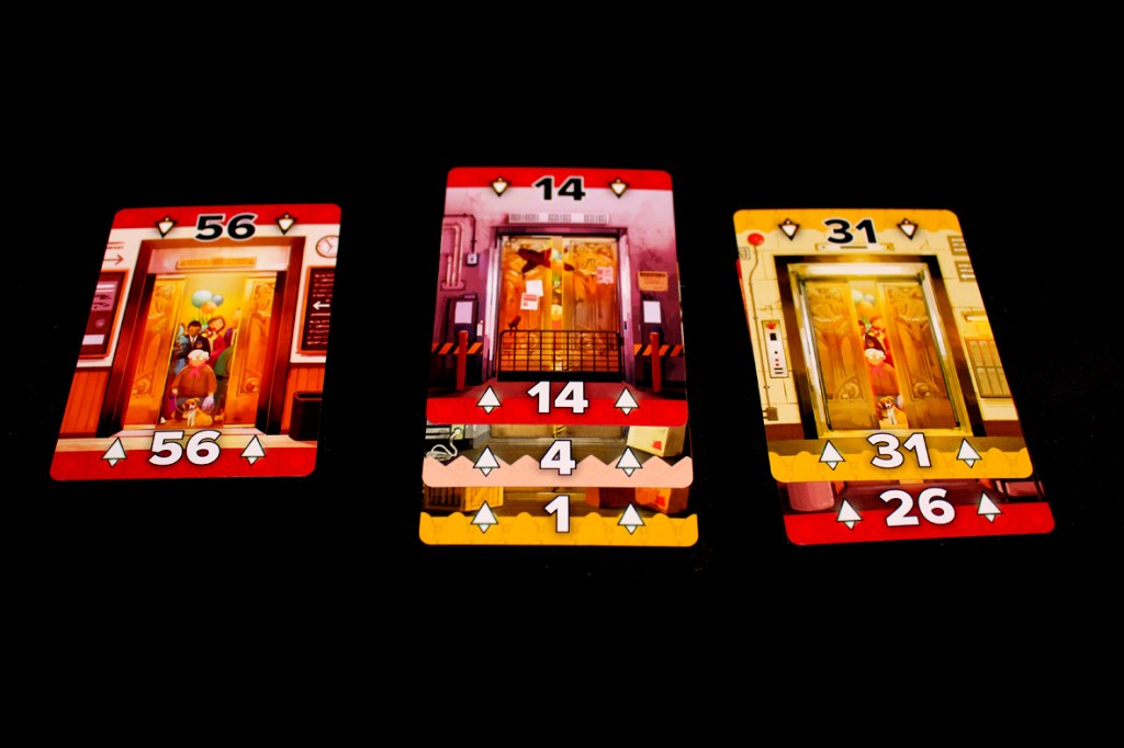 Three game cards featuring colorful illustrations of elevators, with numbers 56, 14, and 31 displayed prominently. The cards depict various characters and settings related to the elevator theme.