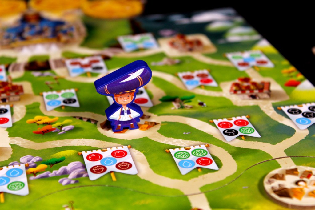 Colorful board game layout featuring a cheerful character in a blue hat standing on a green path, surrounded by various game pieces and banners displaying icons for resources.