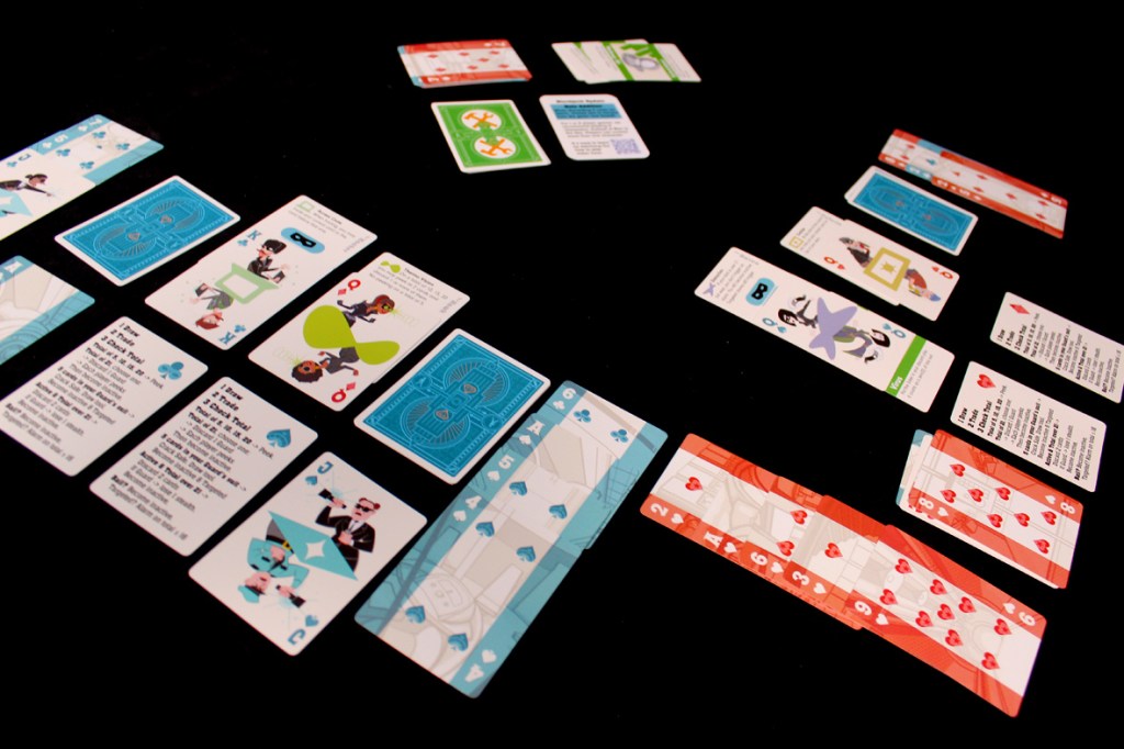 A tabletop scene showing a variety of playing cards placed in a strategic layout on a black background, featuring colorful graphics and illustrations.