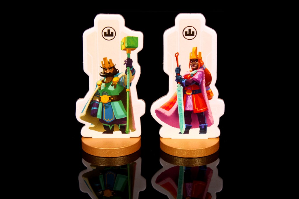 Two colorful game pieces depicting kings, one holding a staff and the other holding a sword, displayed on a reflective surface.