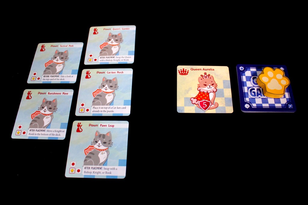 A layout of game cards from Cat's Gambit: Queen Aurelia, featuring several Paw cards with instructions, and the main Queen Aurelia card showing her score.