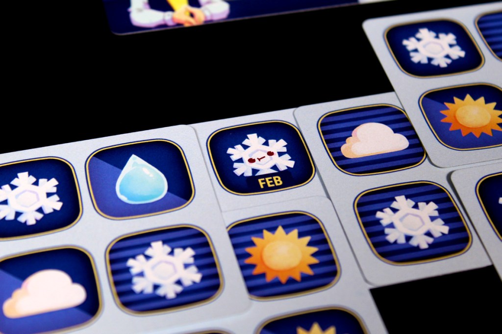 Close-up of a digital game board featuring weather icons, including snowflakes, a water droplet, clouds, and suns, with a label for February.