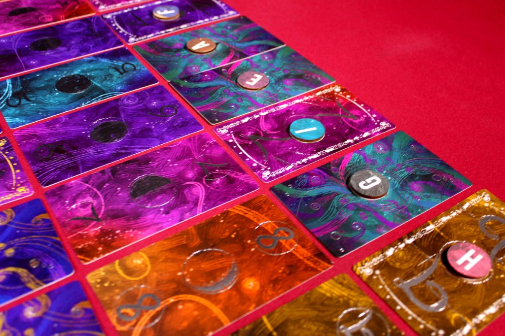 Colorful playing cards arranged on a red surface, featuring abstract designs and various numbers.