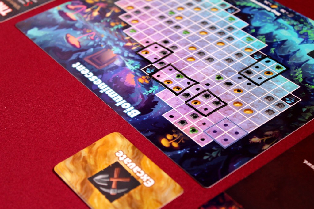 A board game layout featuring a colorful game board with a grid pattern and various icons. A card labeled 'Excavation' is visible in the foreground.