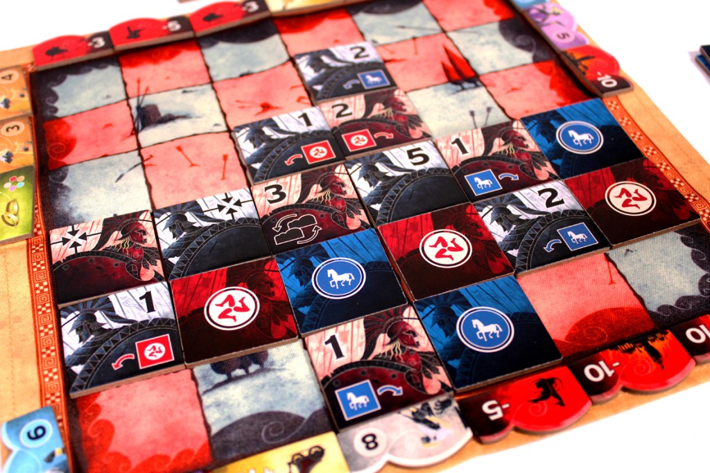 A close-up view of a colorful board game featuring a grid of tiles, some with numbers and various symbols, set against a background of dark and light colors.