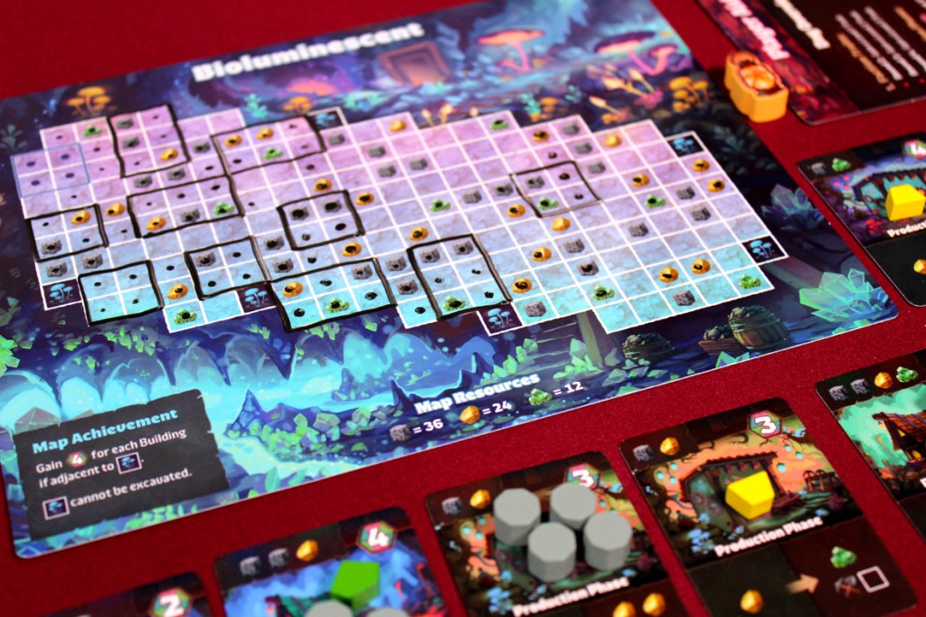 A colorful tabletop game board featuring a grid map titled 'Bioluminescent' with various resource icons, surrounded by game cards detailing achievements and production phases.