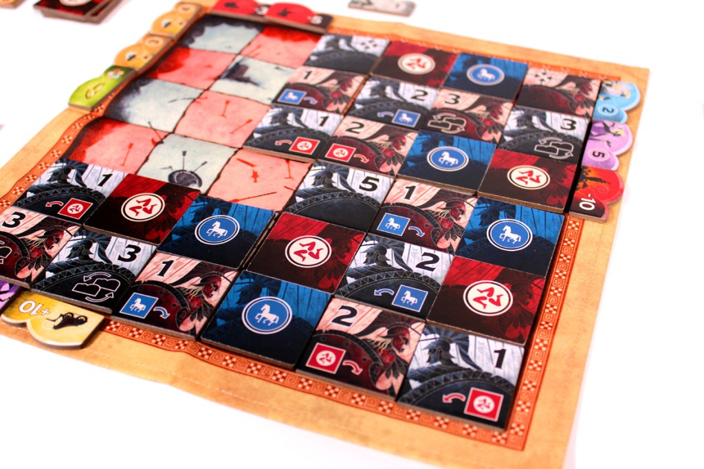 Close-up of a board game showing a grid with various colored tiles, numbers, and icons on it, indicating player moves and resources.