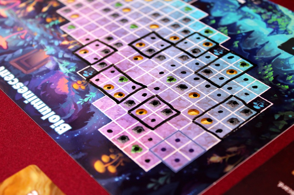 A close-up of a colorful board game showing a grid layout with various markings and colored dots, set on a vibrant, illustrated background.