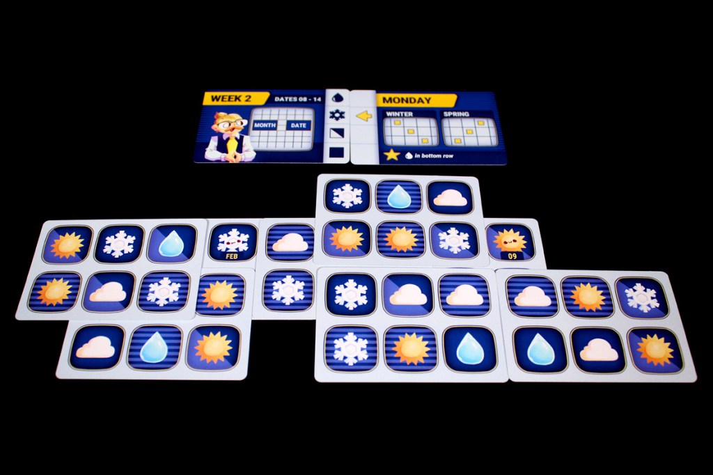 A game board featuring various weather icons, including sun, clouds, snowflakes, and raindrops, arranged in a grid layout. A schedule card indicating 'Week 2' and specifying dates with a section for 'Monday' and seasons.