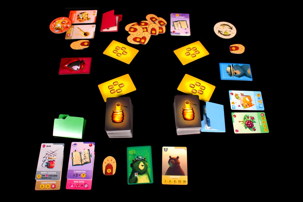 A tabletop game setup featuring various cards, including animal characters and game pieces, arranged on a black surface.