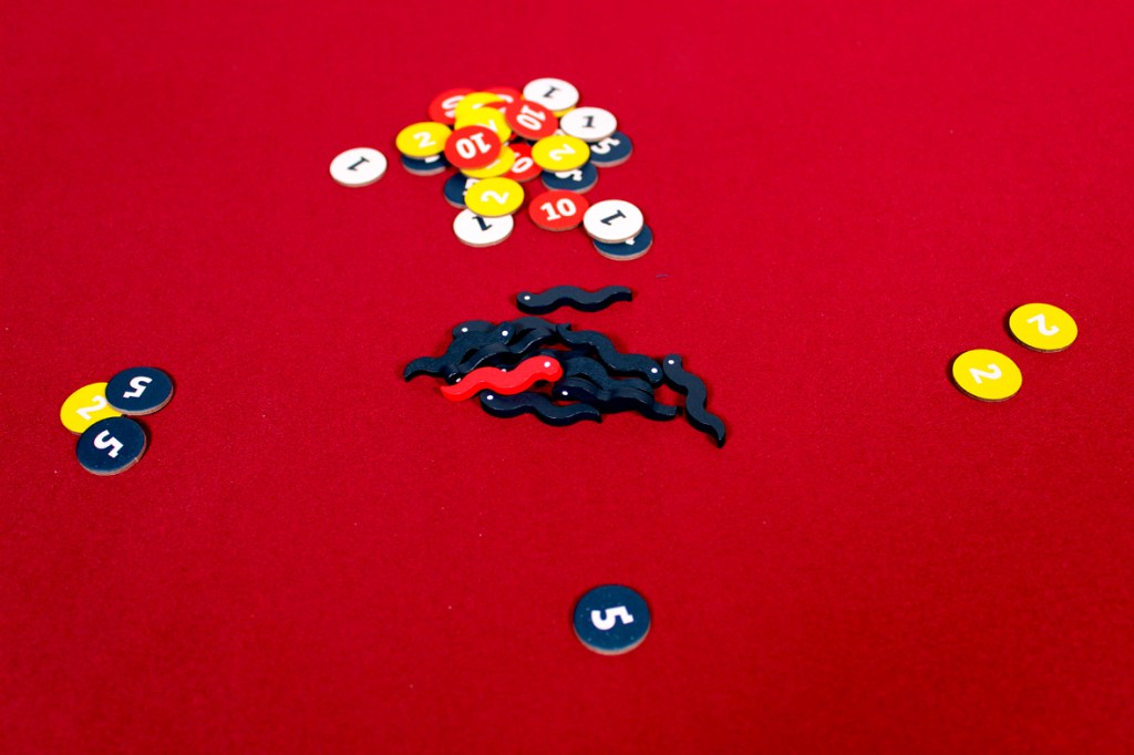 Colorful game tokens on a red table, featuring numbers and squiggly shapes.