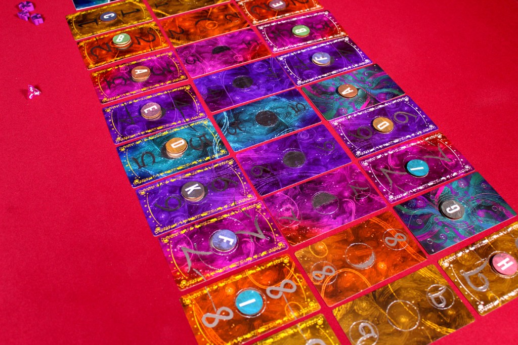 A colorful array of game cards organized in a grid pattern on a red surface, featuring various symbols and letters.