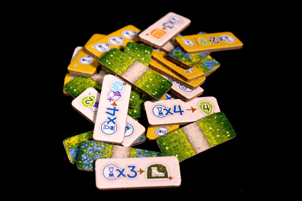 A collection of colorful game tokens featuring various symbols and numbers, scattered on a black surface.