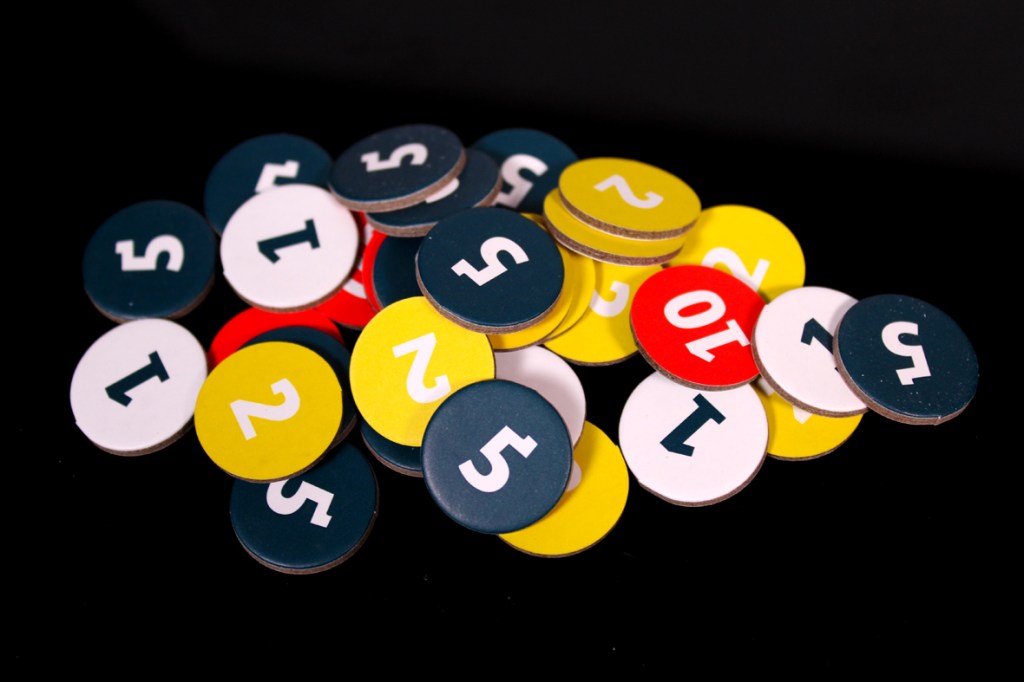 A colorful assortment of circular tokens with numbers printed on them, including ones in red, yellow, and blue, scattered on a dark surface.