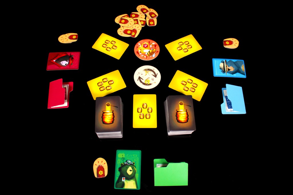 A tabletop game setup featuring various cards and tokens, including yellow cards, red and blue folders, and a round game piece in the center, all displayed on a black background.