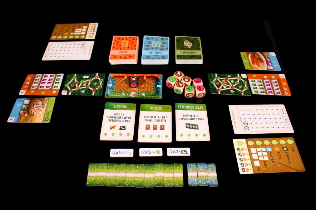 A tabletop board game setup featuring various cards, tokens, and a scoring pad arranged on a black background, showcasing gameplay elements and objectives.