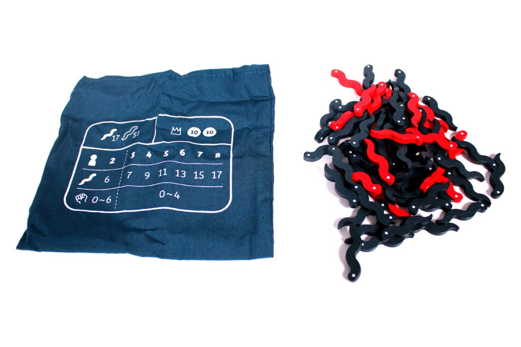 A blue fabric bag with a printed game board design on it, alongside a pile of black and red curved game pieces.