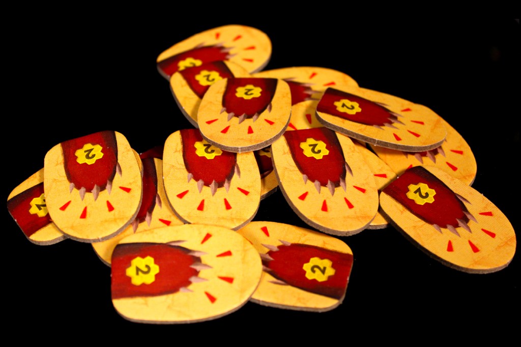 A pile of decorative tokens featuring a red and yellow bear paw with the number 2 prominently displayed.